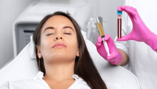 Beautician will do PRP therapy for the face against wrinkles
and against hair loss of a beautiful woman in beauty salon.Doctor holds test tubes with venous blood and blood plasma.Cosmetology concept.